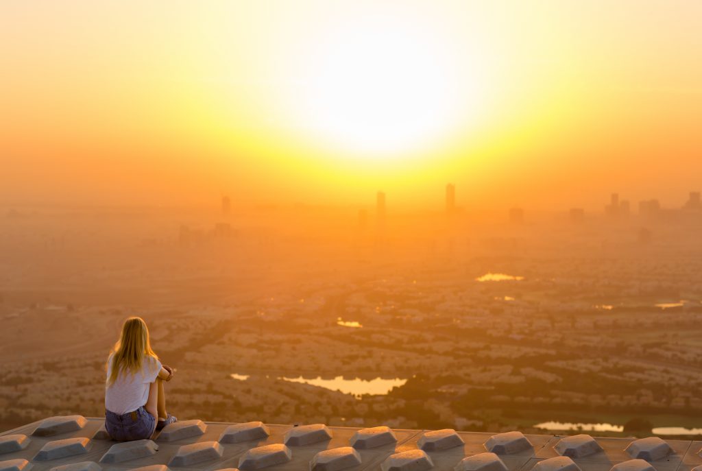 Female Solo Traveller Looking Over a City Sunset